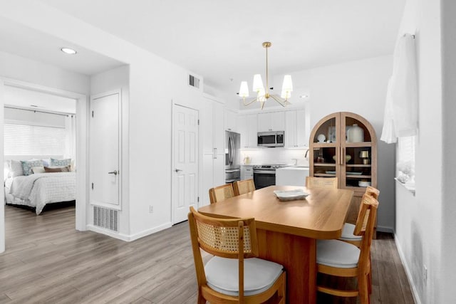 dining space with an inviting chandelier and light hardwood / wood-style flooring