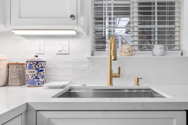 details with tasteful backsplash, sink, and white cabinets