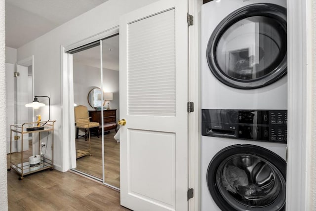 washroom with stacked washing maching and dryer and wood-type flooring