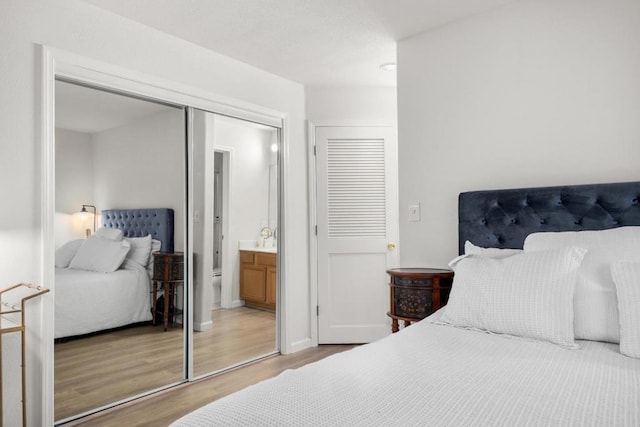 bedroom featuring ensuite bath and wood-type flooring