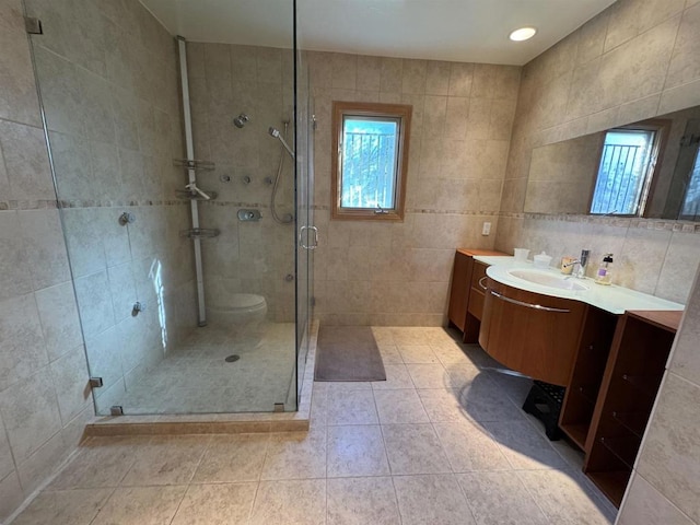 bathroom with tile walls, vanity, tile patterned flooring, and a shower with door