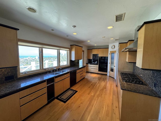 kitchen featuring sink, wall chimney range hood, backsplash, and black appliances