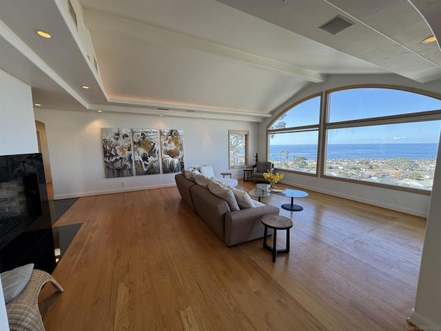 living room featuring light wood-type flooring, lofted ceiling with beams, and a water view