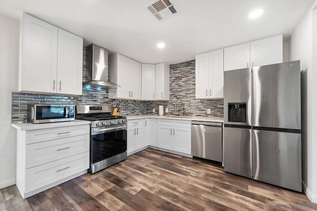 kitchen with wall chimney exhaust hood, sink, white cabinetry, stainless steel appliances, and decorative backsplash