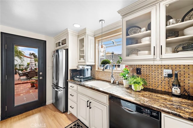 kitchen with sink, stainless steel fridge, dishwasher, hanging light fixtures, and dark stone counters