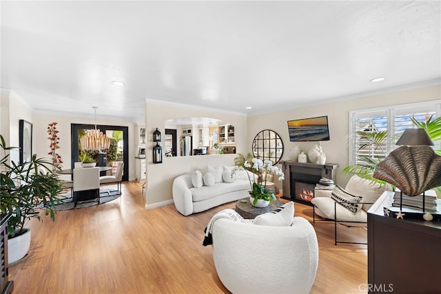 living room featuring a notable chandelier, crown molding, and light wood-type flooring