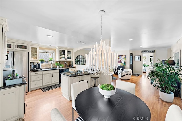 dining room featuring sink, light hardwood / wood-style flooring, and a notable chandelier