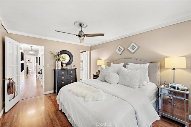 bedroom featuring hardwood / wood-style flooring, ornamental molding, and ceiling fan with notable chandelier