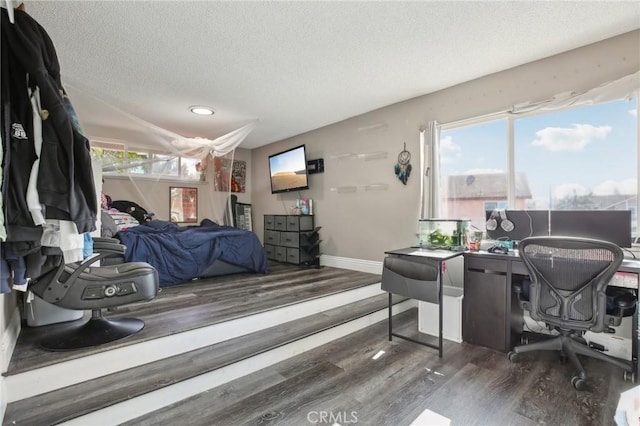 bedroom featuring multiple windows, dark hardwood / wood-style floors, and a textured ceiling