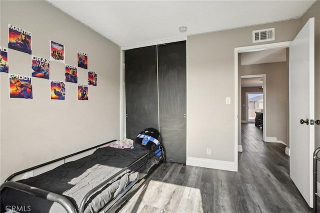 bedroom with dark hardwood / wood-style flooring and a closet