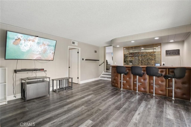 bar with dark hardwood / wood-style floors and a textured ceiling