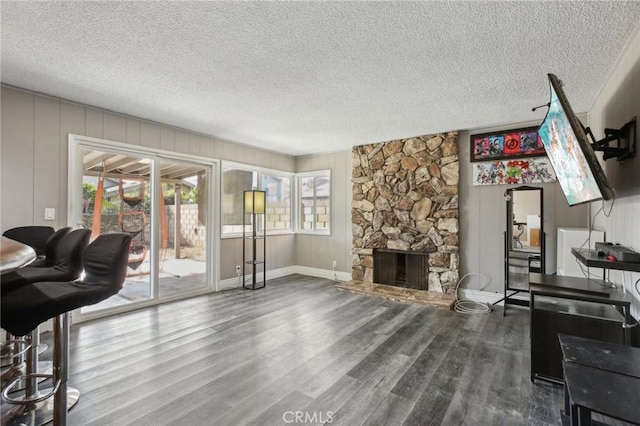 living room featuring hardwood / wood-style flooring, a stone fireplace, a textured ceiling, and a wealth of natural light