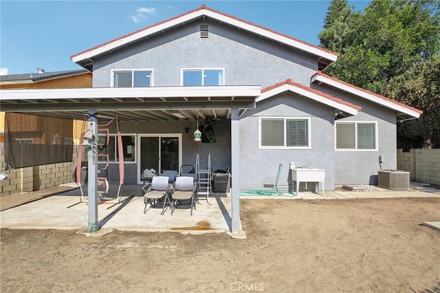 back of property featuring cooling unit, sink, and a patio