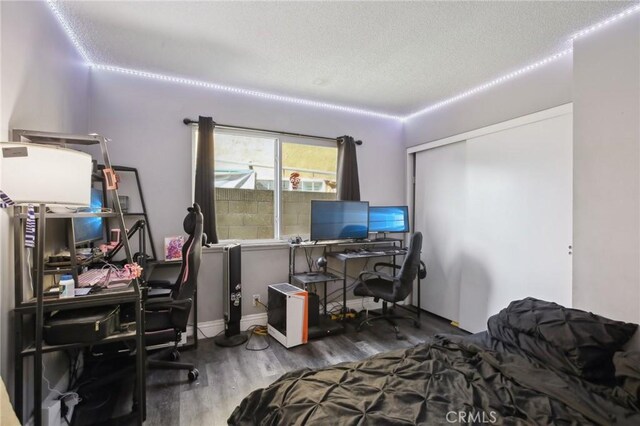 bedroom with a closet, dark hardwood / wood-style floors, and a textured ceiling