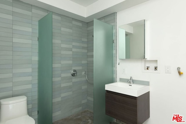 bathroom with vanity, a tile shower, and toilet