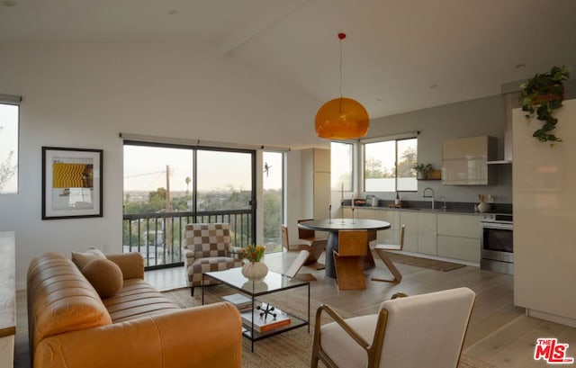 living room with beamed ceiling, high vaulted ceiling, sink, and light hardwood / wood-style flooring