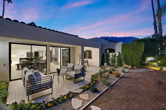 back house at dusk with an outdoor living space, a patio area, and a mountain view