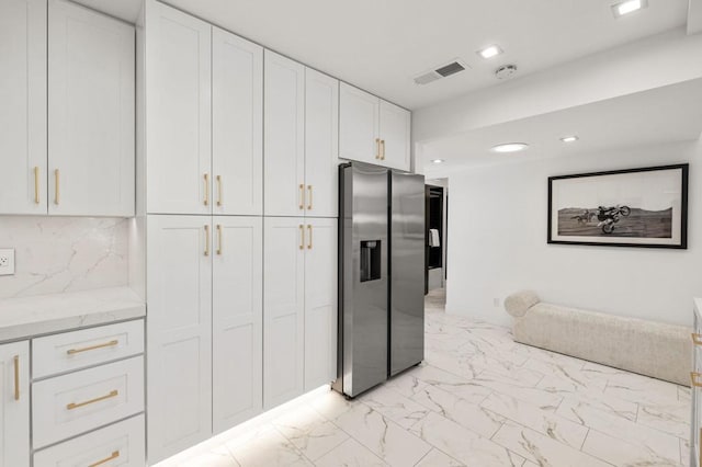 kitchen featuring white cabinetry, stainless steel fridge, light stone countertops, and tasteful backsplash