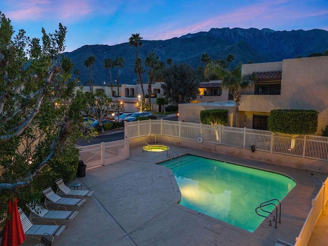 pool at dusk with a mountain view and a patio area