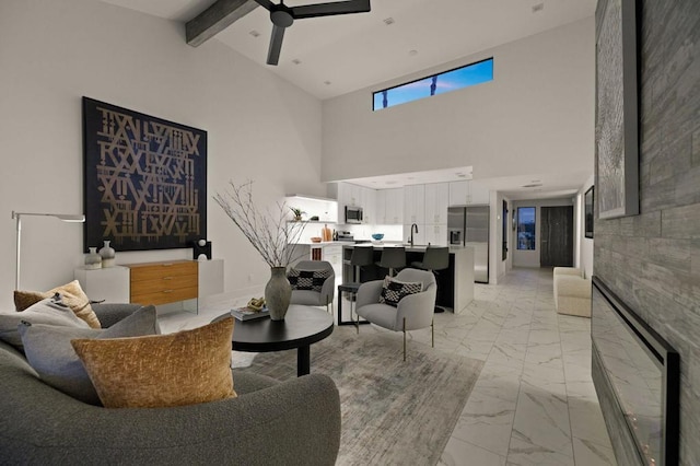 living room featuring beamed ceiling, high vaulted ceiling, sink, and ceiling fan