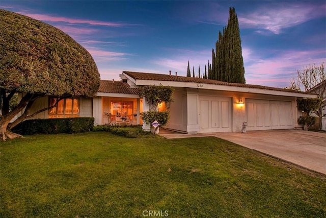 ranch-style home with a garage and a yard