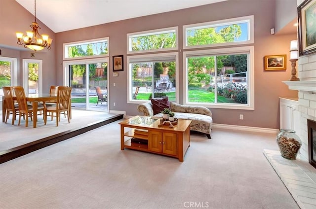 living room featuring a brick fireplace, high vaulted ceiling, light colored carpet, and a chandelier