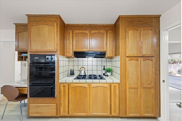 kitchen with black gas stovetop, decorative backsplash, ventilation hood, and tile countertops