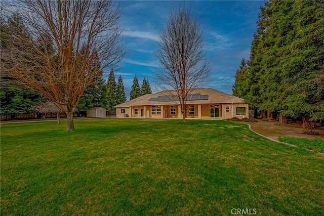 view of front of home with a front yard, a shed, and solar panels