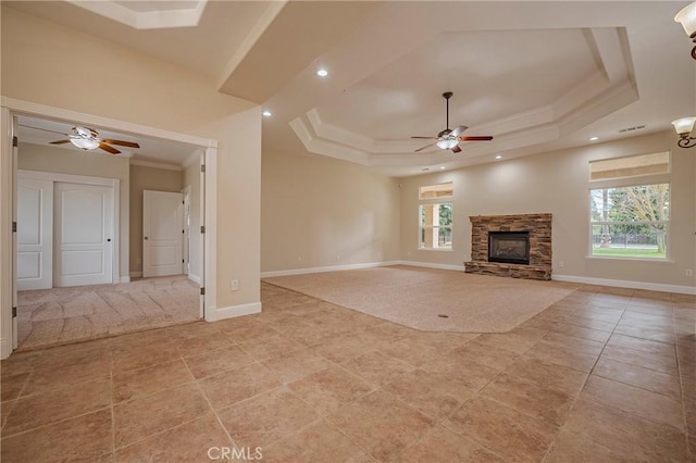 unfurnished living room featuring a fireplace, a tray ceiling, a wealth of natural light, and ornamental molding