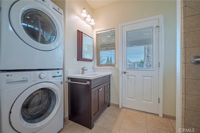 clothes washing area featuring stacked washer and clothes dryer, sink, and light tile patterned floors