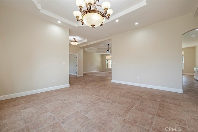 unfurnished room featuring ceiling fan with notable chandelier and a raised ceiling