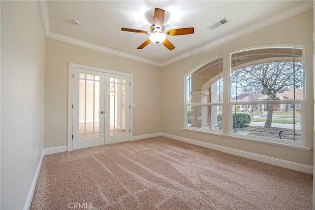 carpeted spare room featuring crown molding, ceiling fan, and french doors