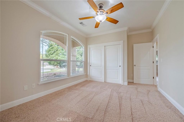 unfurnished bedroom featuring ornamental molding, light carpet, ceiling fan, and a closet