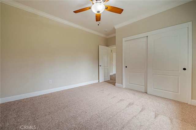 unfurnished bedroom with crown molding, light colored carpet, ceiling fan, and a closet