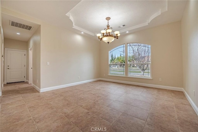 tiled spare room featuring a raised ceiling and a notable chandelier