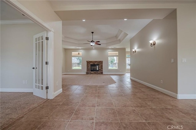 unfurnished living room featuring crown molding, a fireplace, ceiling fan, and a tray ceiling