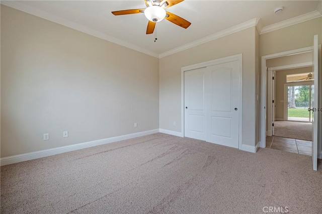 unfurnished bedroom with crown molding, carpet flooring, ceiling fan, and a closet