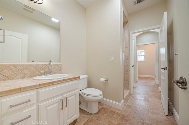 bathroom featuring walk in shower, toilet, tasteful backsplash, vanity, and tile patterned flooring