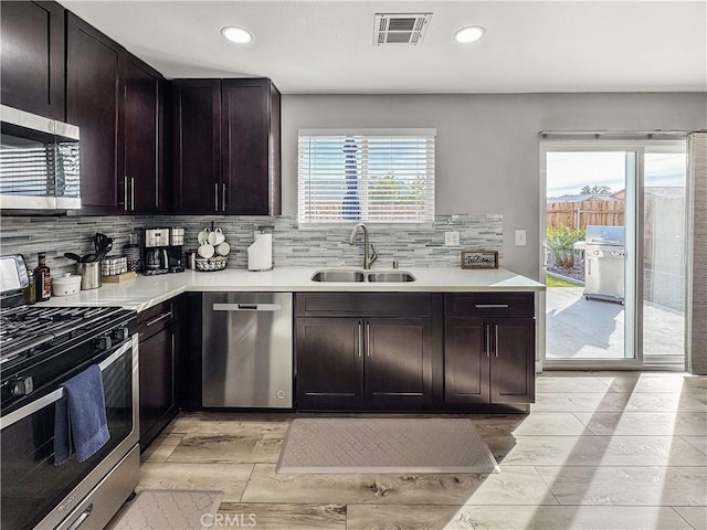 kitchen with dark brown cabinetry, sink, a wealth of natural light, and appliances with stainless steel finishes