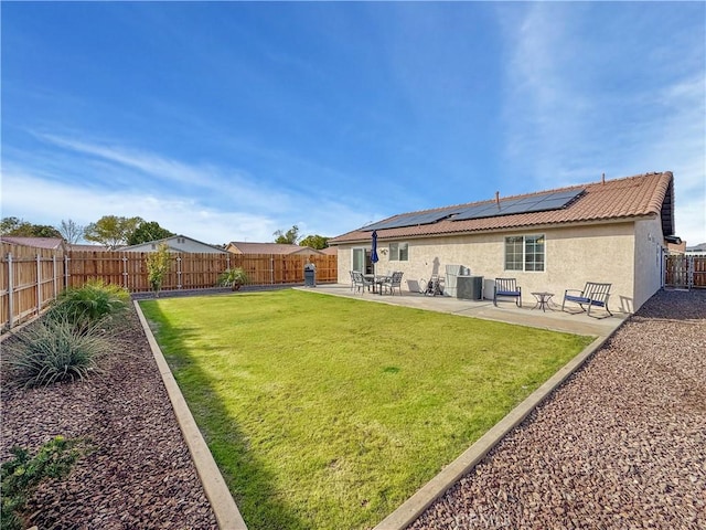 back of property featuring a yard, central AC unit, a patio area, and solar panels