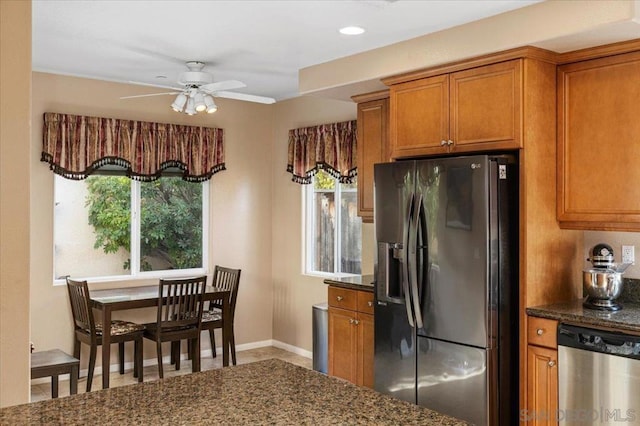 kitchen with dark stone countertops, ceiling fan, appliances with stainless steel finishes, and a wealth of natural light