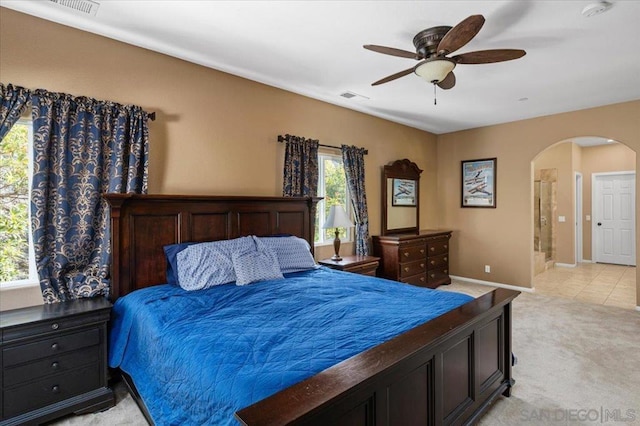 bedroom featuring ceiling fan, light colored carpet, and ensuite bathroom