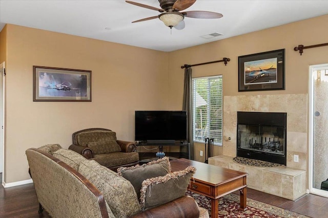 living room featuring ceiling fan, a fireplace, and dark hardwood / wood-style flooring