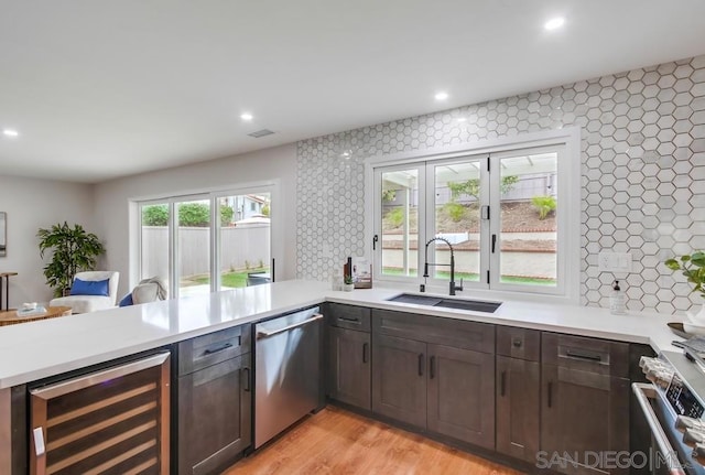 kitchen with appliances with stainless steel finishes, sink, beverage cooler, and backsplash