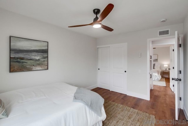 bedroom with ceiling fan, dark hardwood / wood-style flooring, and a closet