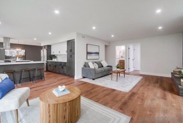 living room with an inviting chandelier and light wood-type flooring