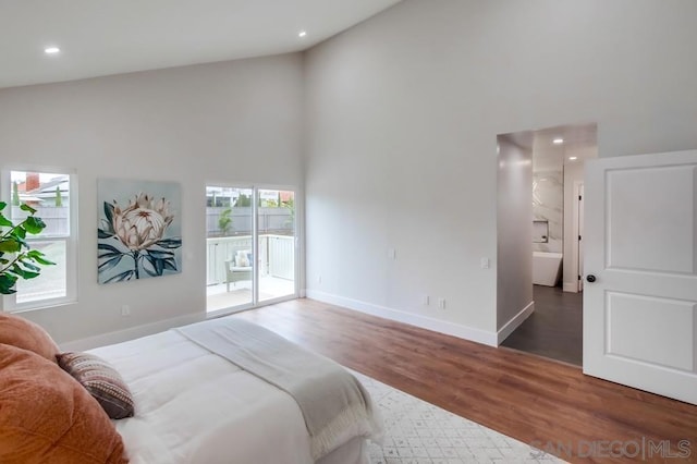 bedroom featuring dark hardwood / wood-style flooring, access to exterior, and high vaulted ceiling