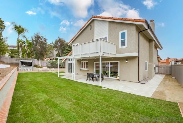 rear view of house featuring a patio, a balcony, and a lawn