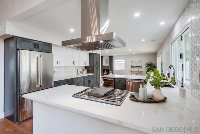 kitchen with stainless steel appliances, a wealth of natural light, island range hood, and kitchen peninsula