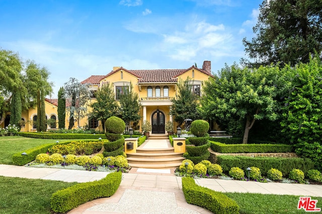 mediterranean / spanish house with a balcony and a front lawn